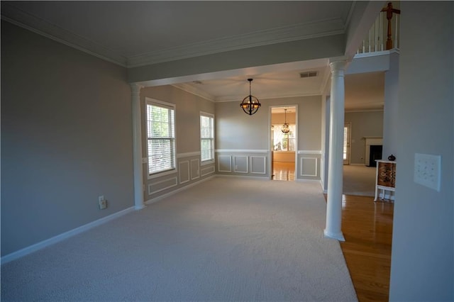 carpeted empty room with ornamental molding, visible vents, decorative columns, and a notable chandelier