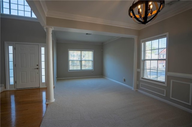foyer entrance featuring decorative columns, baseboards, ornamental molding, and a chandelier
