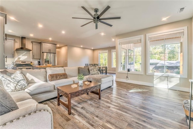 living room with light wood-style flooring, recessed lighting, visible vents, and baseboards