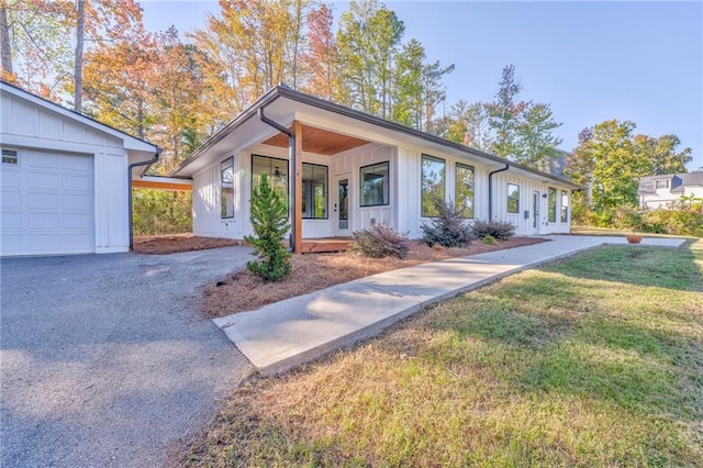 view of front facade featuring a garage, board and batten siding, a front yard, and aphalt driveway