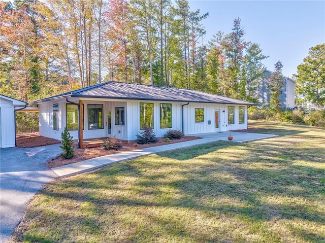 view of front of house featuring a front yard, a standing seam roof, covered porch, board and batten siding, and metal roof