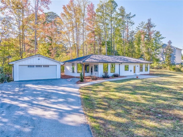 single story home featuring a porch, a garage, an outdoor structure, and a front lawn