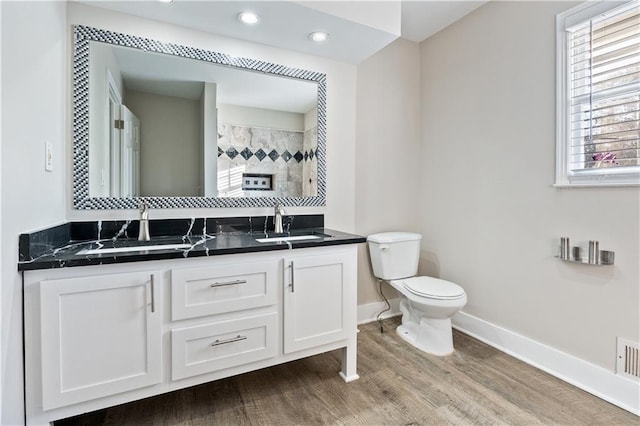 bathroom with tiled shower, vanity, hardwood / wood-style flooring, and toilet