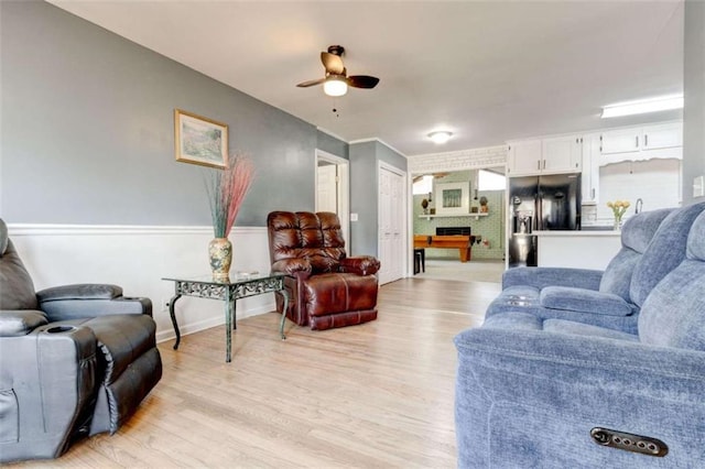 living room with a ceiling fan, baseboards, and light wood finished floors