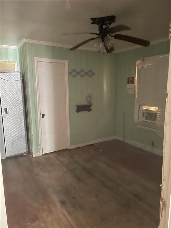 empty room with wood finished floors, cooling unit, crown molding, baseboards, and ceiling fan