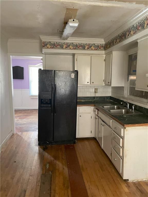 kitchen featuring a sink, dark countertops, ornamental molding, and black fridge