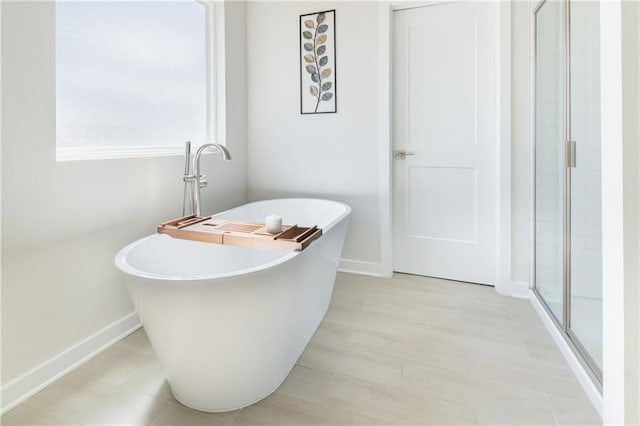 bathroom featuring baseboards, a stall shower, and a soaking tub