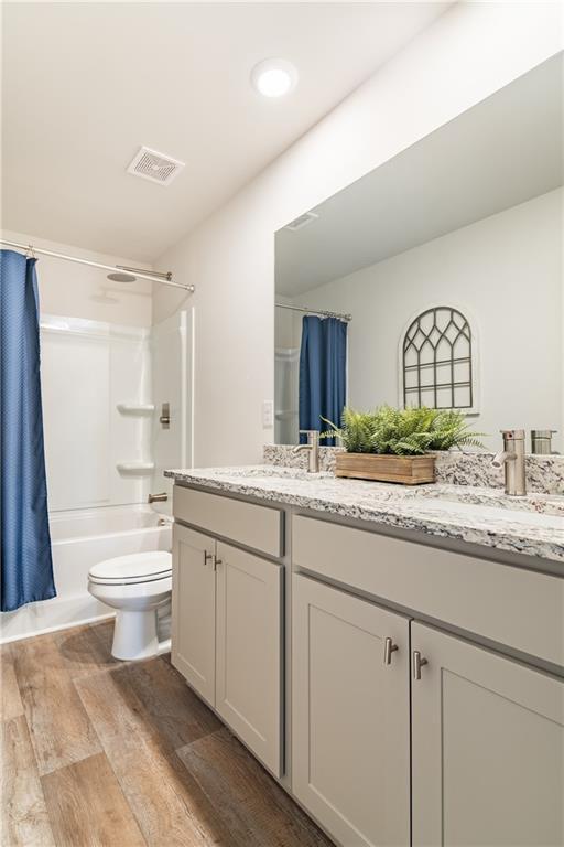bathroom with double vanity, a sink, visible vents, and wood finished floors