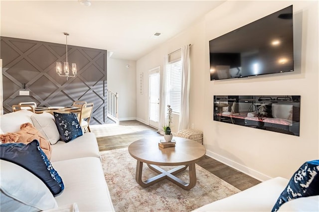 living room featuring baseboards, an inviting chandelier, and wood finished floors