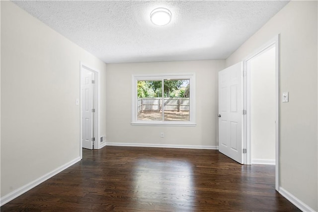 empty room with dark hardwood / wood-style flooring and a textured ceiling