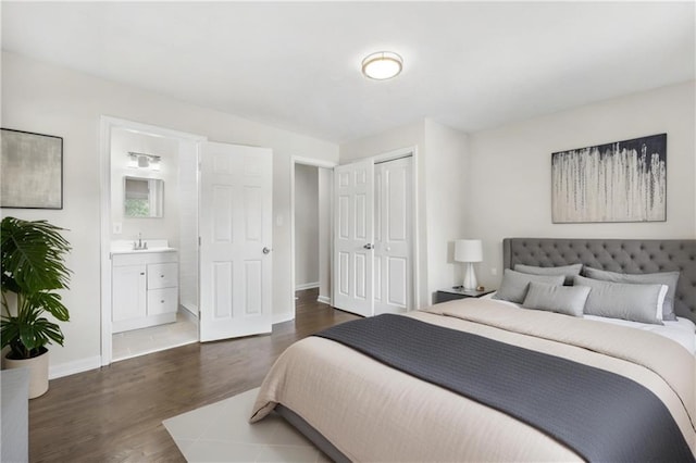 bedroom featuring dark hardwood / wood-style flooring, ensuite bathroom, a closet, and sink