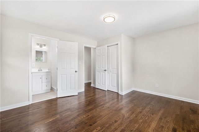 unfurnished bedroom featuring dark hardwood / wood-style floors, connected bathroom, and a closet