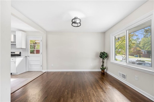 unfurnished dining area with dark hardwood / wood-style flooring and plenty of natural light