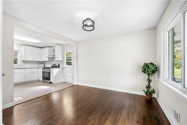 kitchen with stainless steel range, wood-type flooring, white cabinets, and plenty of natural light