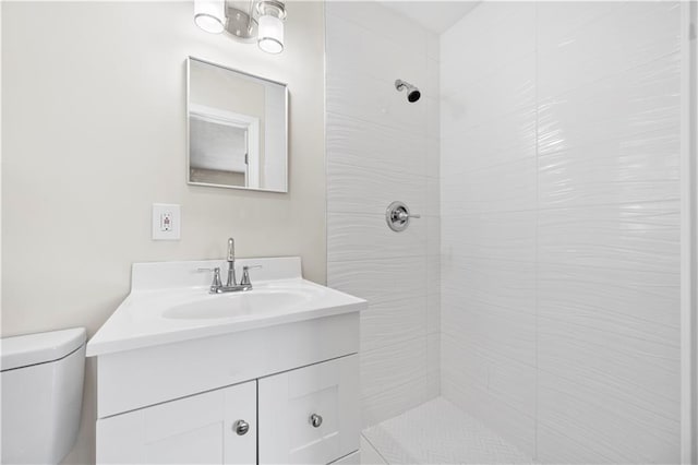 bathroom featuring tiled shower, vanity, and toilet