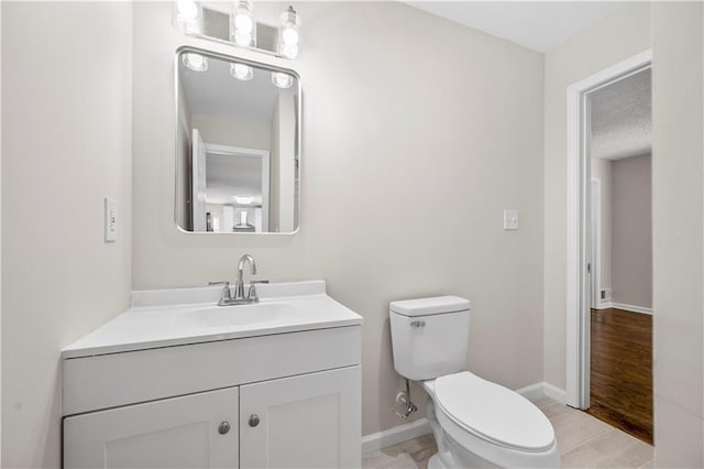 bathroom with hardwood / wood-style floors, vanity, toilet, and a textured ceiling