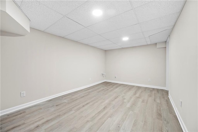 basement featuring a paneled ceiling and light hardwood / wood-style flooring