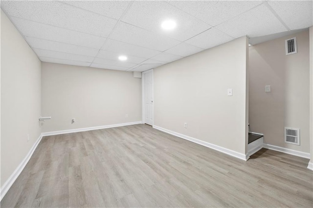 basement with a drop ceiling and light hardwood / wood-style floors