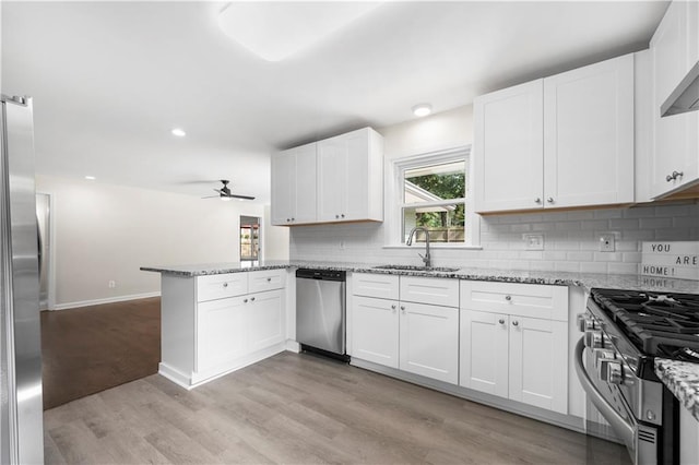 kitchen featuring white cabinets, kitchen peninsula, sink, and appliances with stainless steel finishes