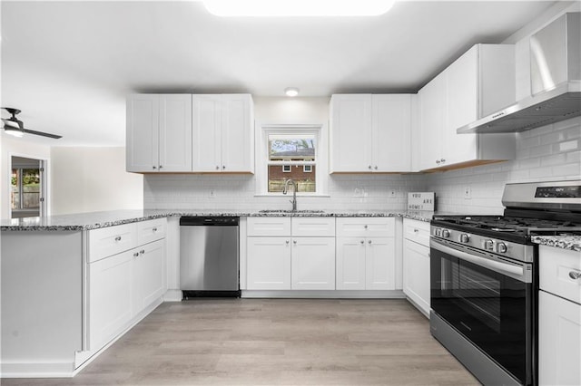 kitchen with wall chimney exhaust hood, white cabinetry, and stainless steel appliances