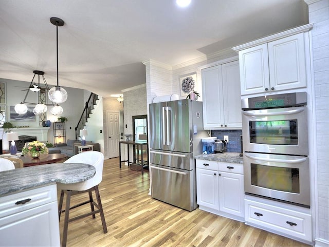 5105 Tynewick Trce NE, Roswell, GA 30075 - kitchen with stainless steel appliances, light wood-type flooring, white cabinets, ornamental molding, and hanging light fixtures