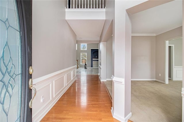 foyer entrance featuring light carpet and ornamental molding