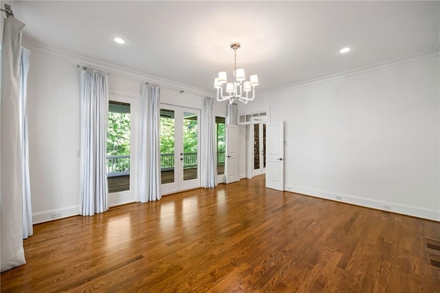 unfurnished room featuring a chandelier, french doors, ornamental molding, baseboards, and wood finished floors