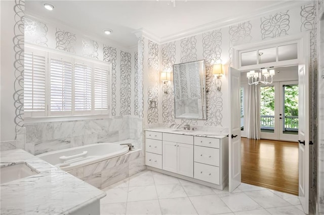 full bath featuring ornamental molding, marble look tile flooring, a bath, two vanities, and a chandelier
