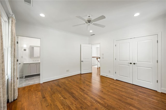 unfurnished bedroom featuring crown molding, wood finished floors, baseboards, connected bathroom, and recessed lighting