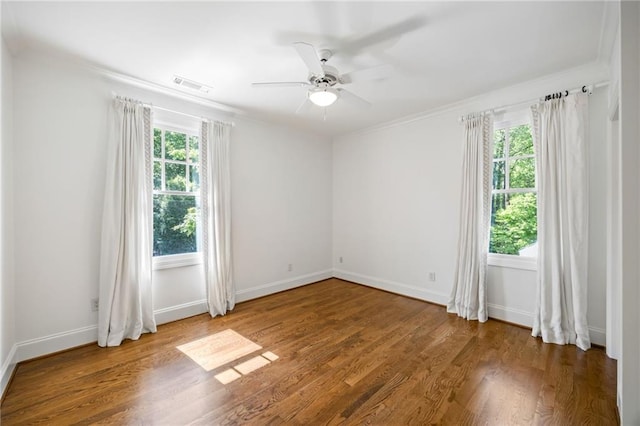 spare room with wood finished floors, a ceiling fan, baseboards, and crown molding