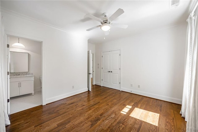 unfurnished bedroom with wood finished floors, baseboards, a sink, connected bathroom, and crown molding