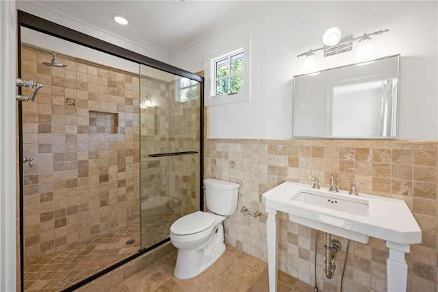 full bathroom featuring a shower stall, tile walls, toilet, crown molding, and wainscoting