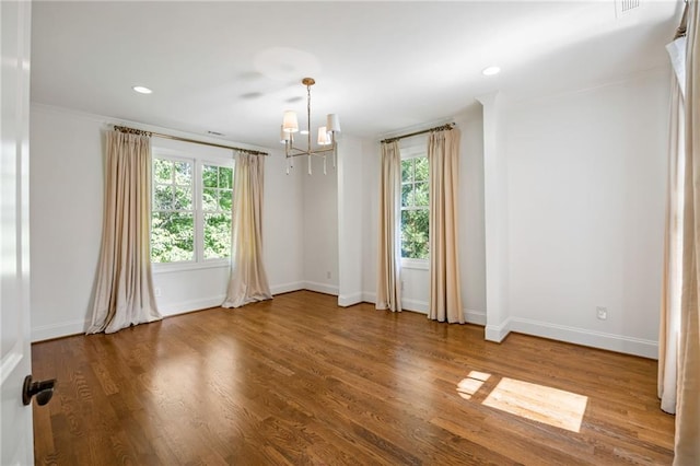 empty room with a chandelier, healthy amount of natural light, baseboards, crown molding, and recessed lighting
