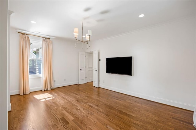 unfurnished living room with a chandelier, baseboards, wood finished floors, ornamental molding, and recessed lighting