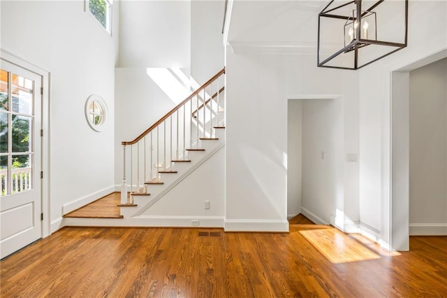 entrance foyer featuring healthy amount of natural light, a chandelier, baseboards, wood finished floors, and a high ceiling