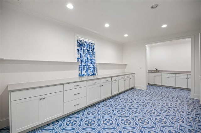 kitchen with white cabinetry, recessed lighting, light countertops, baseboards, and a sink