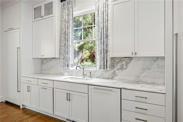 bar with a sink, backsplash, dark wood-style flooring, and dishwasher