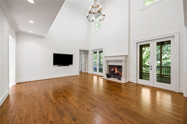 unfurnished living room featuring a chandelier, wood finished floors, a warm lit fireplace, recessed lighting, and baseboards