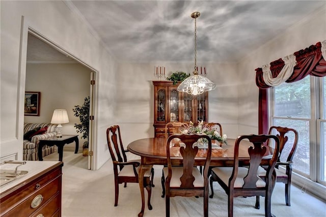 dining room with light colored carpet, crown molding, and an inviting chandelier