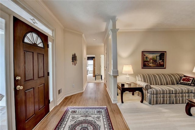 foyer entrance with baseboards, ornamental molding, light wood finished floors, and visible vents