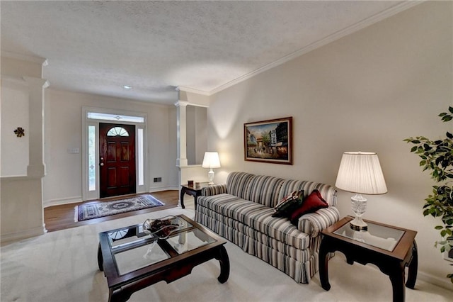 living area with crown molding, a textured ceiling, decorative columns, and baseboards