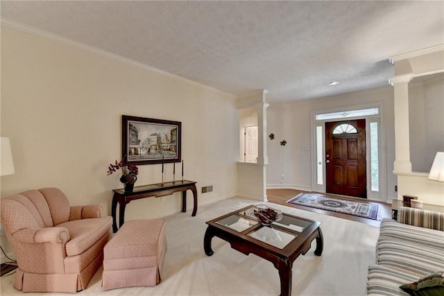 living area with crown molding, ornate columns, and visible vents