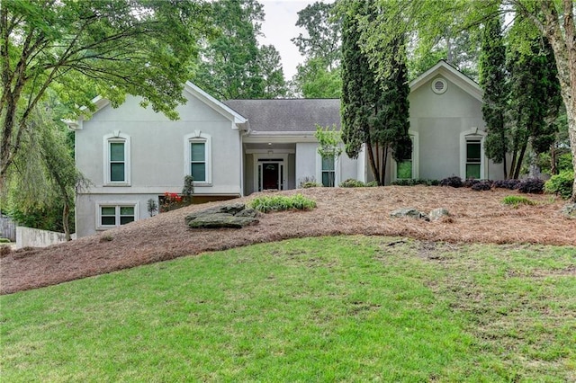 ranch-style home with a front lawn, roof with shingles, and stucco siding