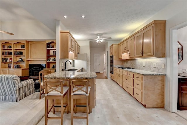 kitchen featuring ceiling fan, a breakfast bar area, gas stovetop, a sink, and a peninsula