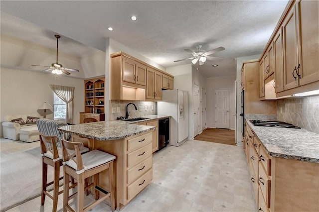 kitchen with a peninsula, ceiling fan, a breakfast bar, and white fridge with ice dispenser