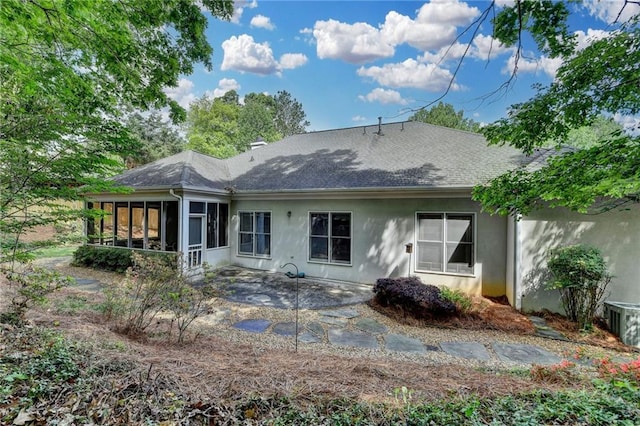 back of property with a shingled roof, a patio, stucco siding, and a sunroom