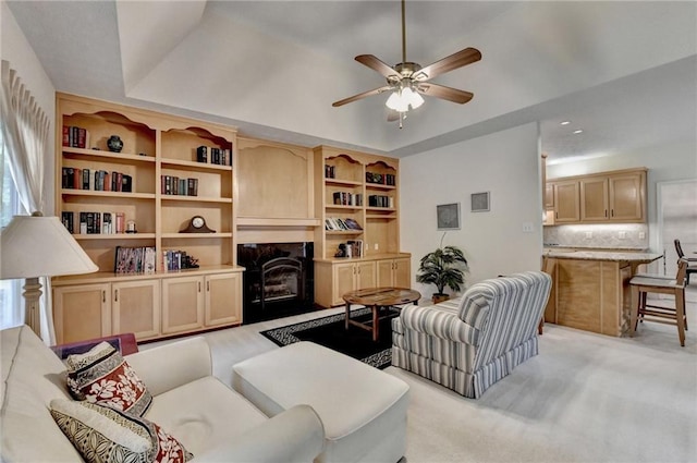 living room with ceiling fan, a tray ceiling, light colored carpet, and a premium fireplace