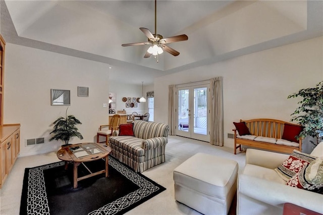 living room featuring ceiling fan, light colored carpet, a tray ceiling, and visible vents
