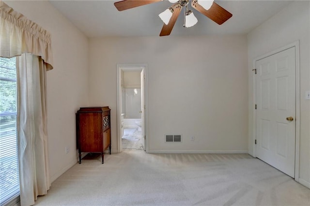unfurnished bedroom featuring baseboards, ensuite bathroom, carpet, and visible vents