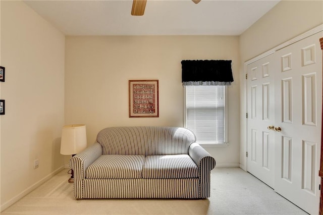living area with carpet floors, baseboards, and a ceiling fan